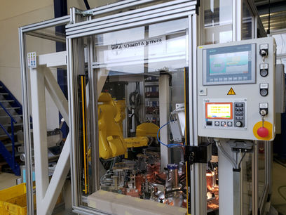 ARF Roboterzelle, Verbundinbetriebnahme der Roboterzelle, welche "Anti-Rotation-Features" (ARFs) auf KFz-Schellen schweißt